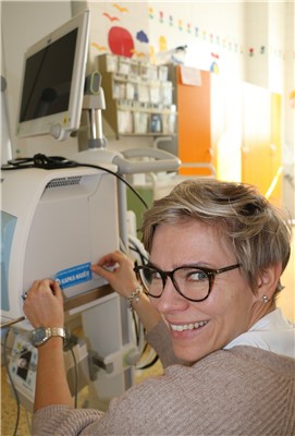 Ředitelka Nadačního fondu Kapka naděje Dita Loudilová nalepuje samolepku na darovaný plicní ventilátor na Dětské klinice v ústecké Masarykově nemocnici.